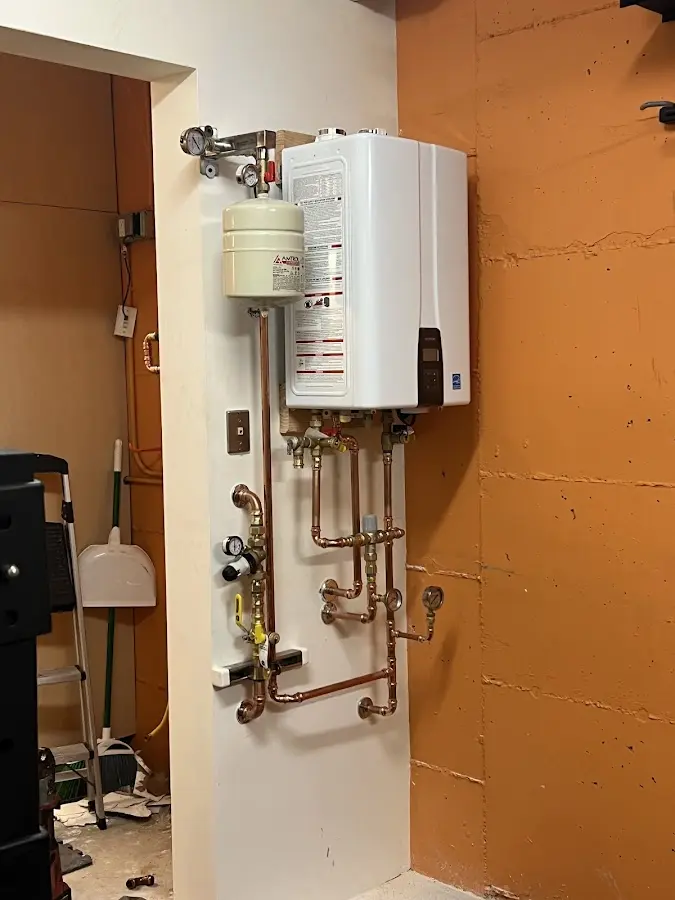 Plumbing technician inspecting water heater connections in Uhrichsville